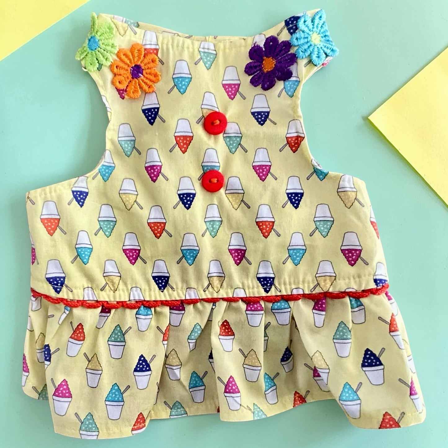 Vestido amarillo para perrita con estampado colorido y detalles de flores en la espalda