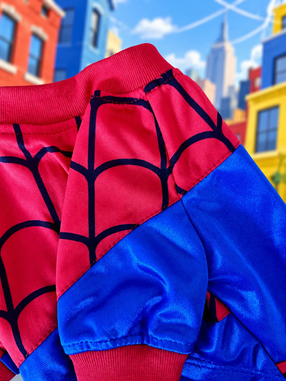 Detalle del disfraz de Spiderman para perro mostrando el estampado de telarañas en color rojo y azul y la textura de la tela