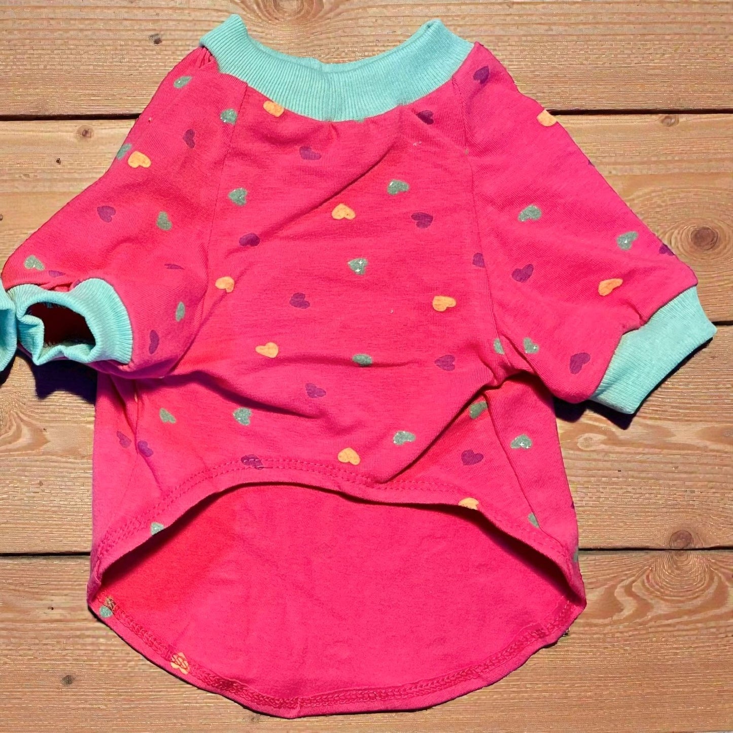 Diseño de playera para perro color rosa vibrante con estampado de corazones y ribetes turquesa