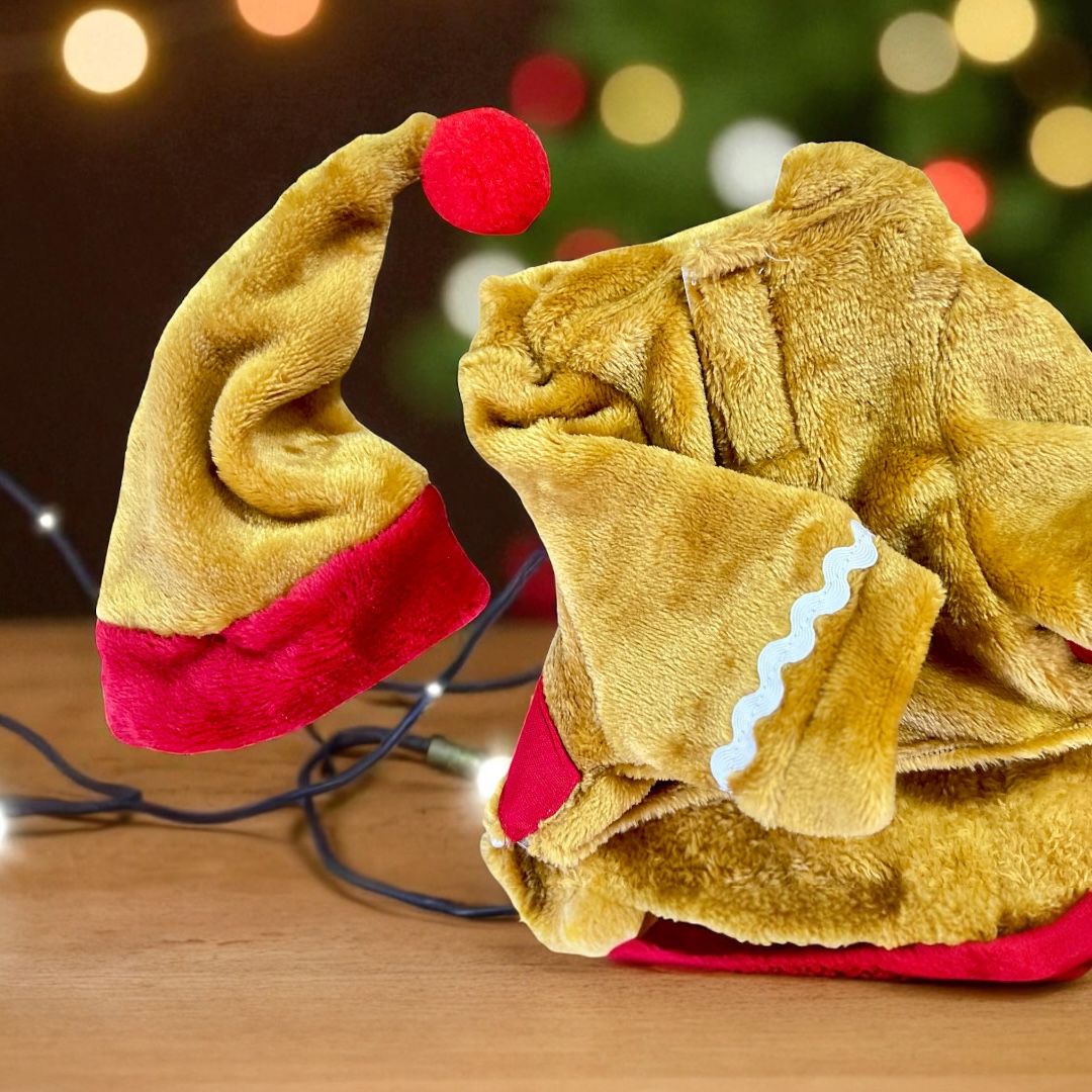 Tela aterciopelada en disfraz de galleta con gorro rojo, detalle artesanal de temporada.
