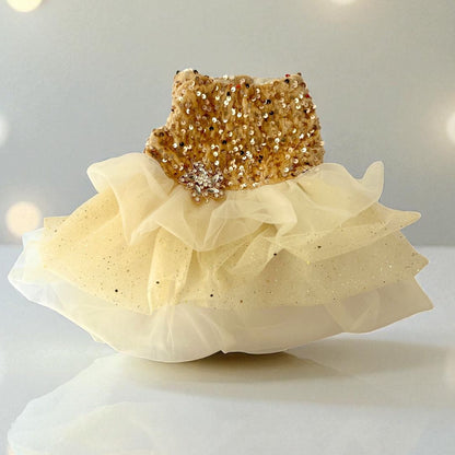 Vestido dorado para perritas con lentejuelas en la parte superior y falda de tul en tonos crema, fotografiado sobre fondo blanco para destacar su brillo.