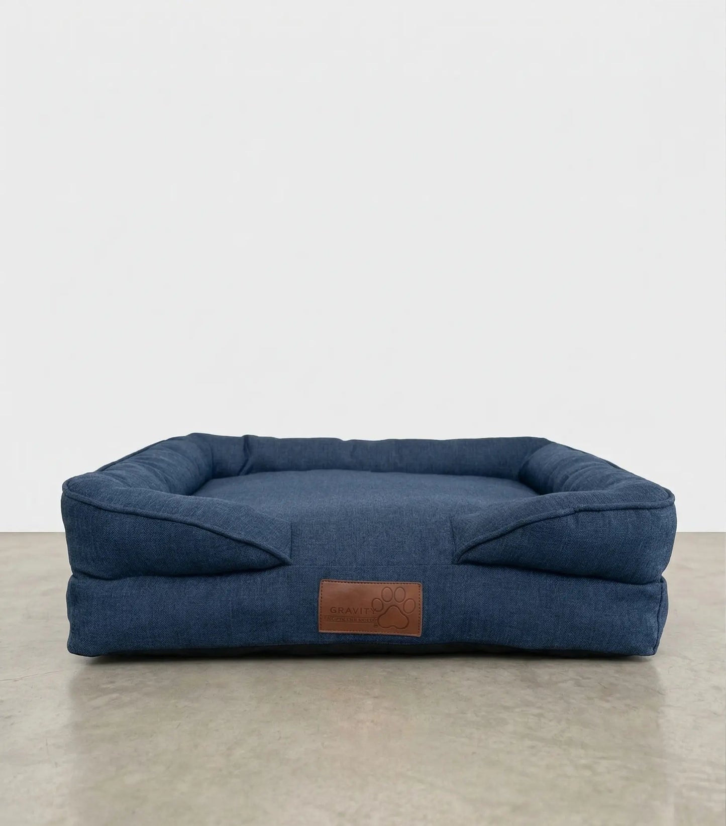 Cama para perro PetUs color azul marino tipo denim con cojín acolchado y parche de piel.
