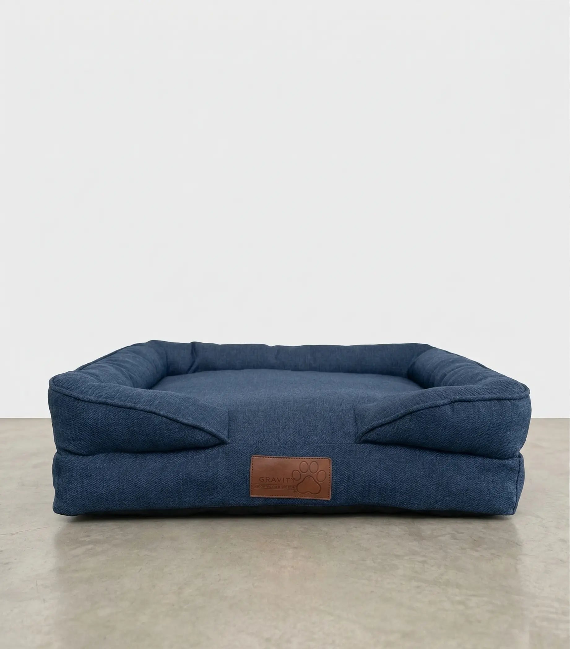 Cama para perro PetUs color azul marino tipo denim con cojín acolchado y parche de piel.