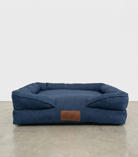 Cama para perro PetUs color azul marino tipo denim con cojín acolchado y parche de piel.