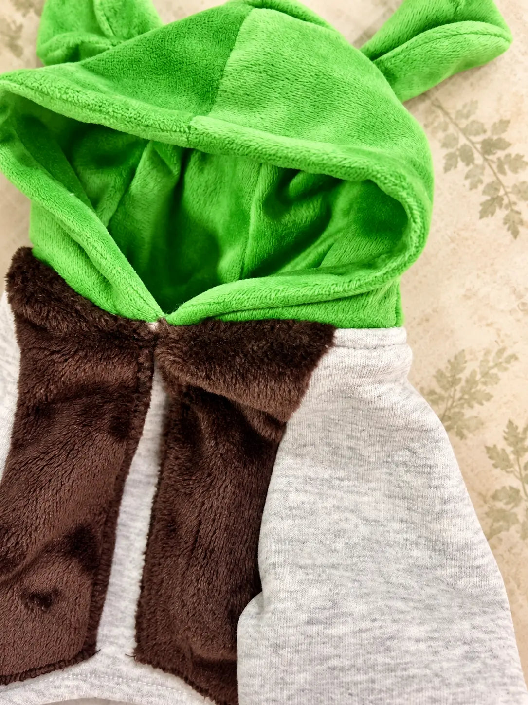 Disfraz de Shrek para perro inspirado en un ogro de cuento de hadas, con chaleco café, camisa blanca y detalles verdes, mostrado de frente.