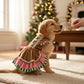 perrito con vestido galletita navideña, frente al arbol de navidad, ambiente calido con luces y regalos