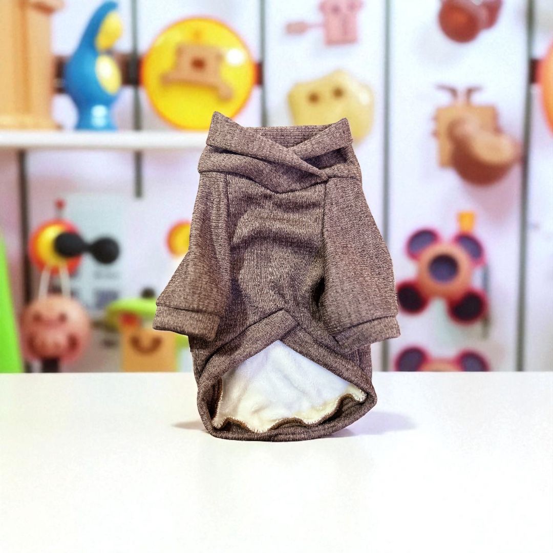 sweater camel para perro exhibido sobre mesa, con interior afelpado y cuello alto, ideal para mantener a tu mascota abrigada en invierno.