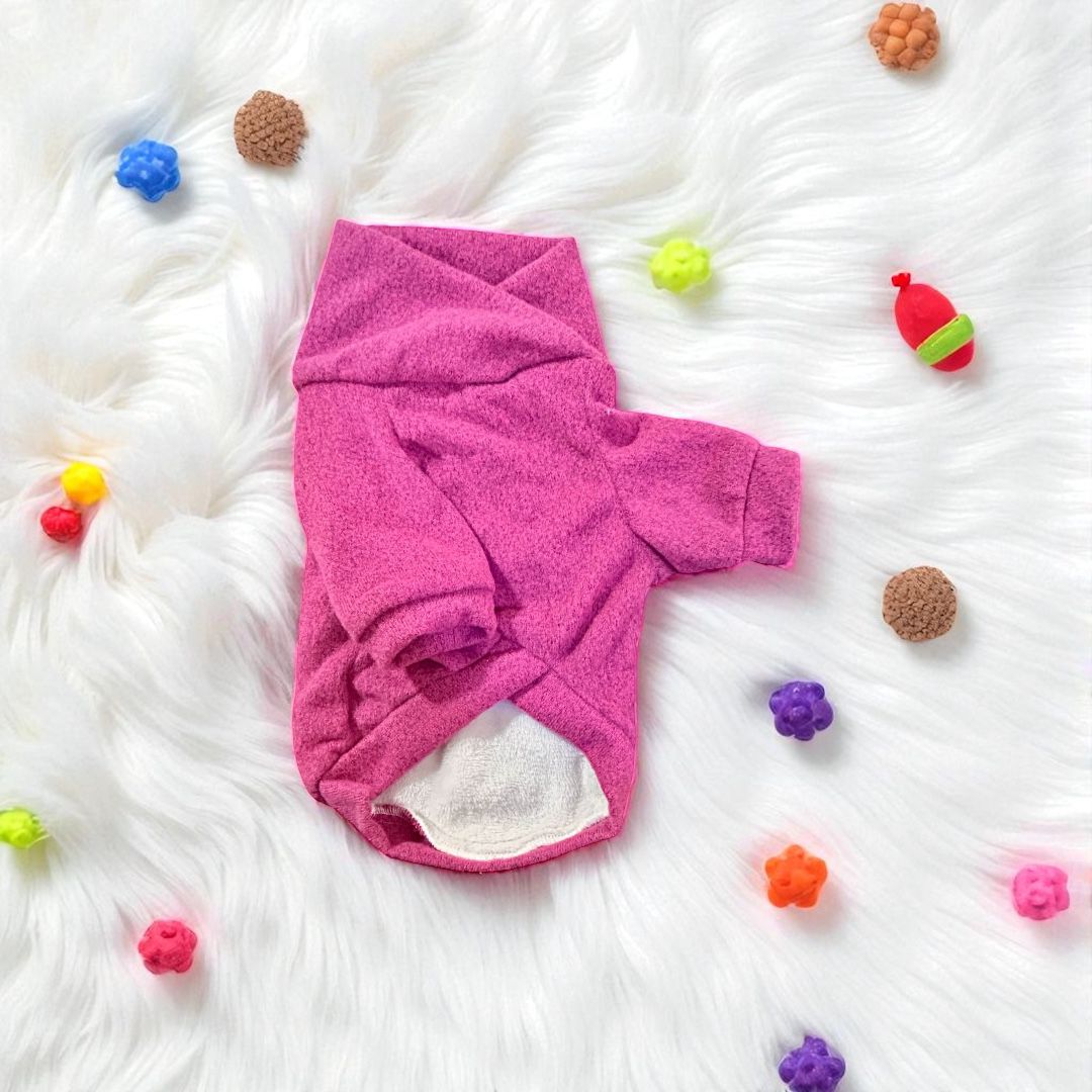 Sueter oslo rosa para perro sobre manta blanca con juguetes de colores