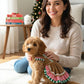 mujer sonriendo junto a su perro vestido con el modelo galletita navideña