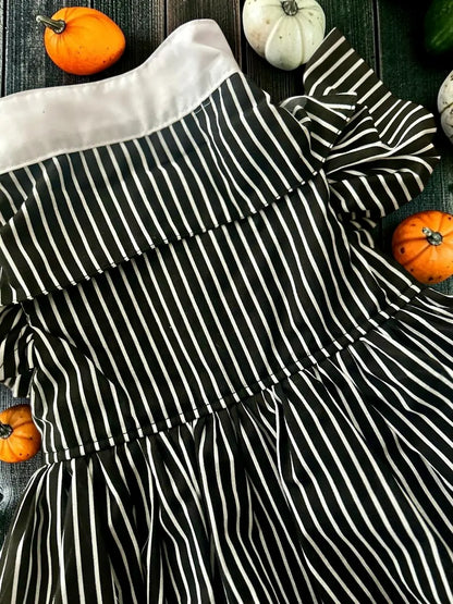 Detalle del disfraz de Jackie para perrita, con tela de rayas negras y blancas, cuello blanco y diseño inspirado en El extraño mundo de Jack, acompañado de elementos decorativos de Halloween.